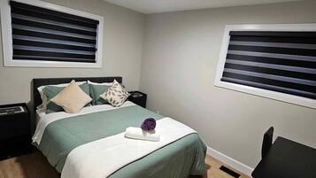 A bedroom with a bed, bedside tables, a chair, and a window with blinds.
