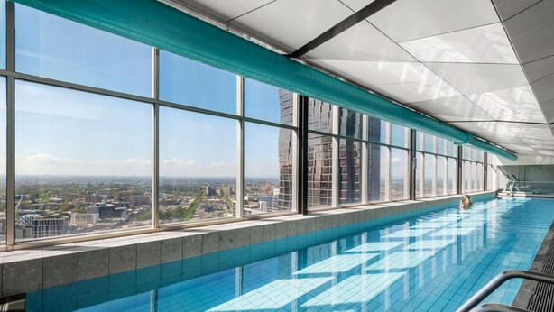 Une longue piscine intérieure dotée de grandes fenêtres offrant une vue sur la ville.
