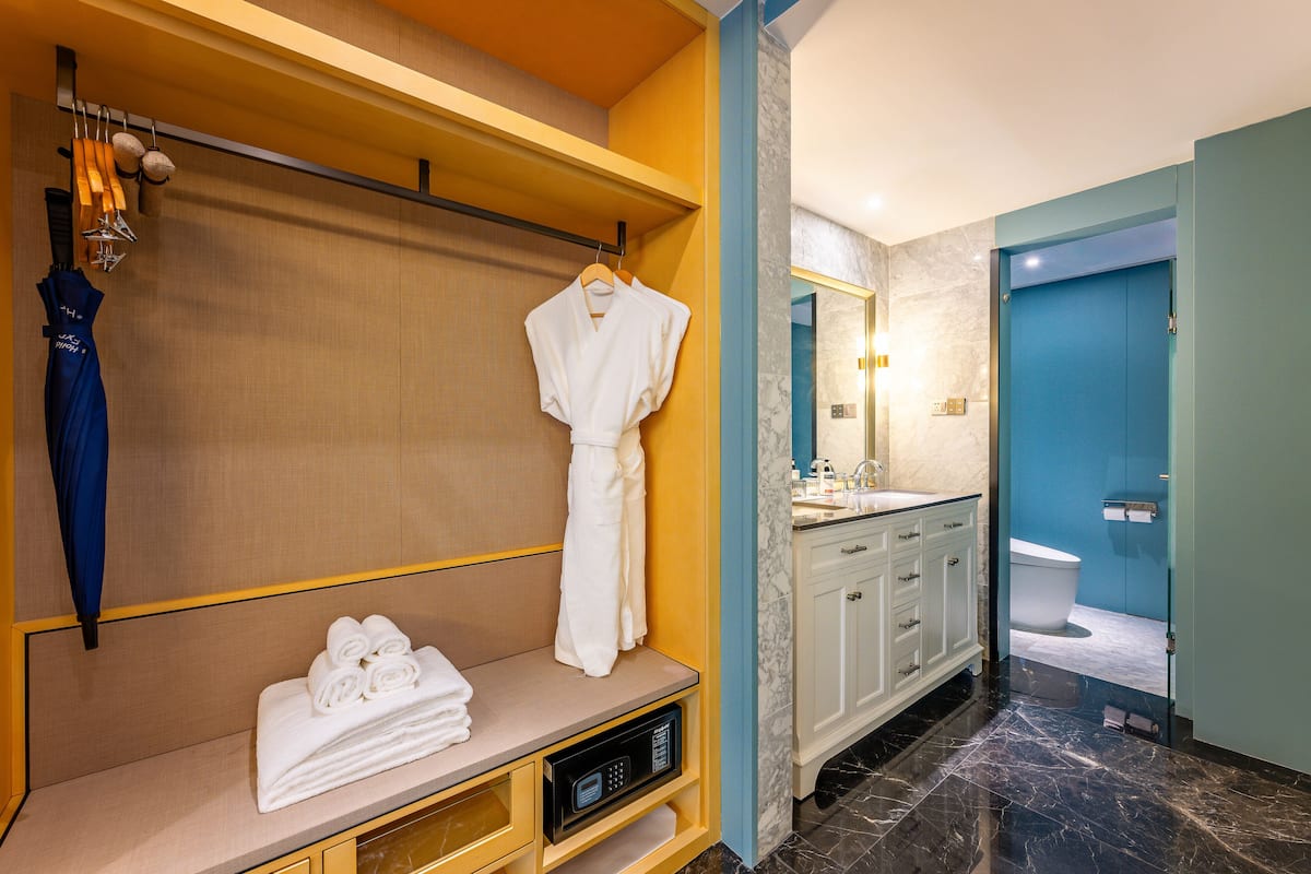 A modern bathroom with a marble floor, a white vanity with a mirror, and a blue door leading to the toilet.