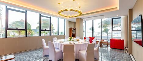 A modern dining area with a round table, white chairs, and a chandelier.