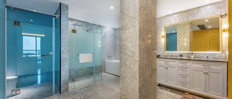 A modern bathroom with a glass shower enclosure, marble flooring, and a large mirror above the sink.