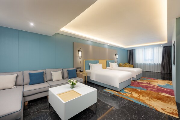 A modern hotel room with a sofa, a bed, a nightstand, and a coffee table.
