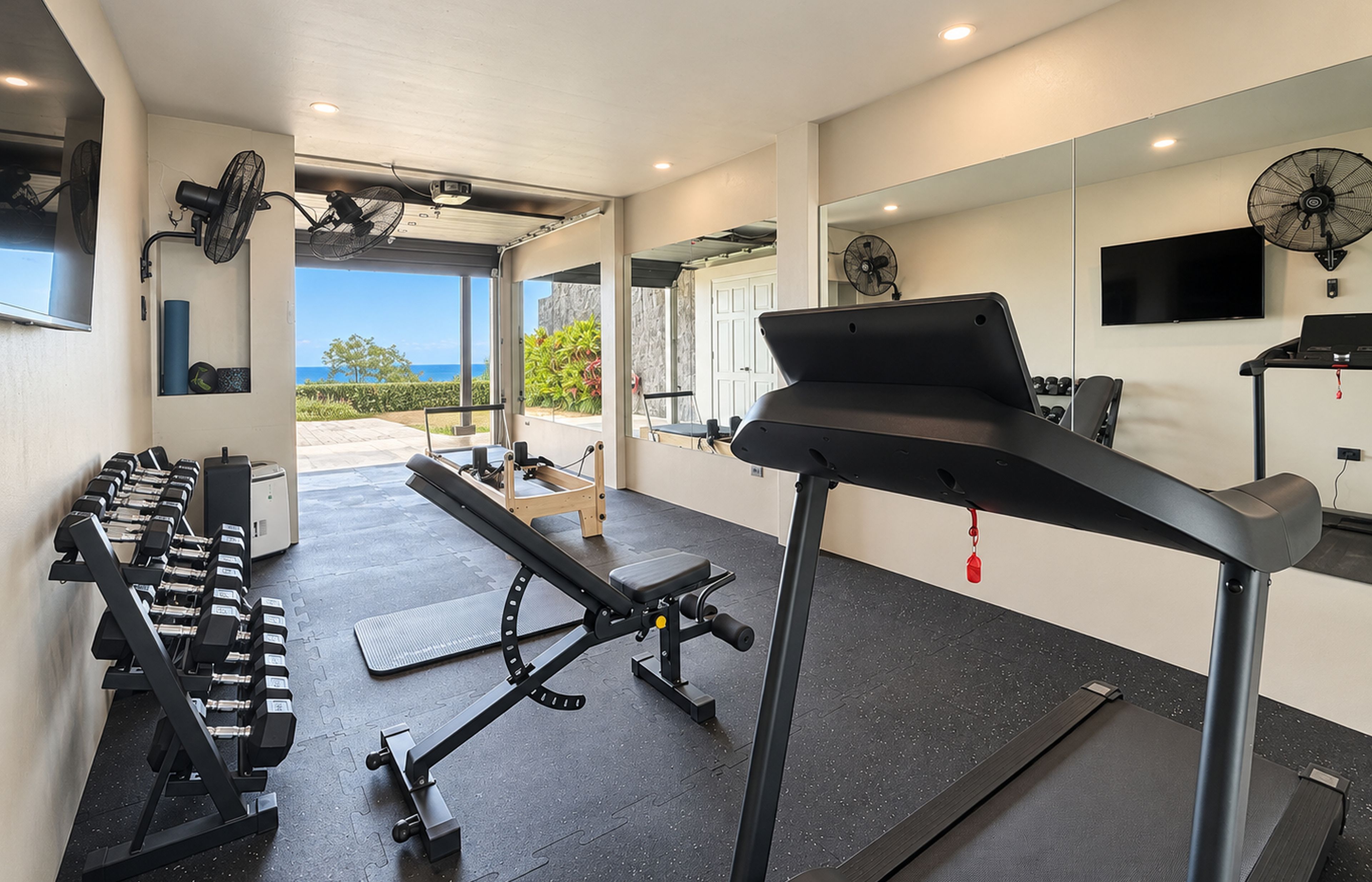 Une salle de sport équipée de matériel d’exercice, d’un tapis de course et offrant une vue sur l’extérieur.