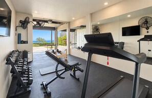 Et fitnesscenter med træningsudstyr, et løbebånd og udsigt til det fri.