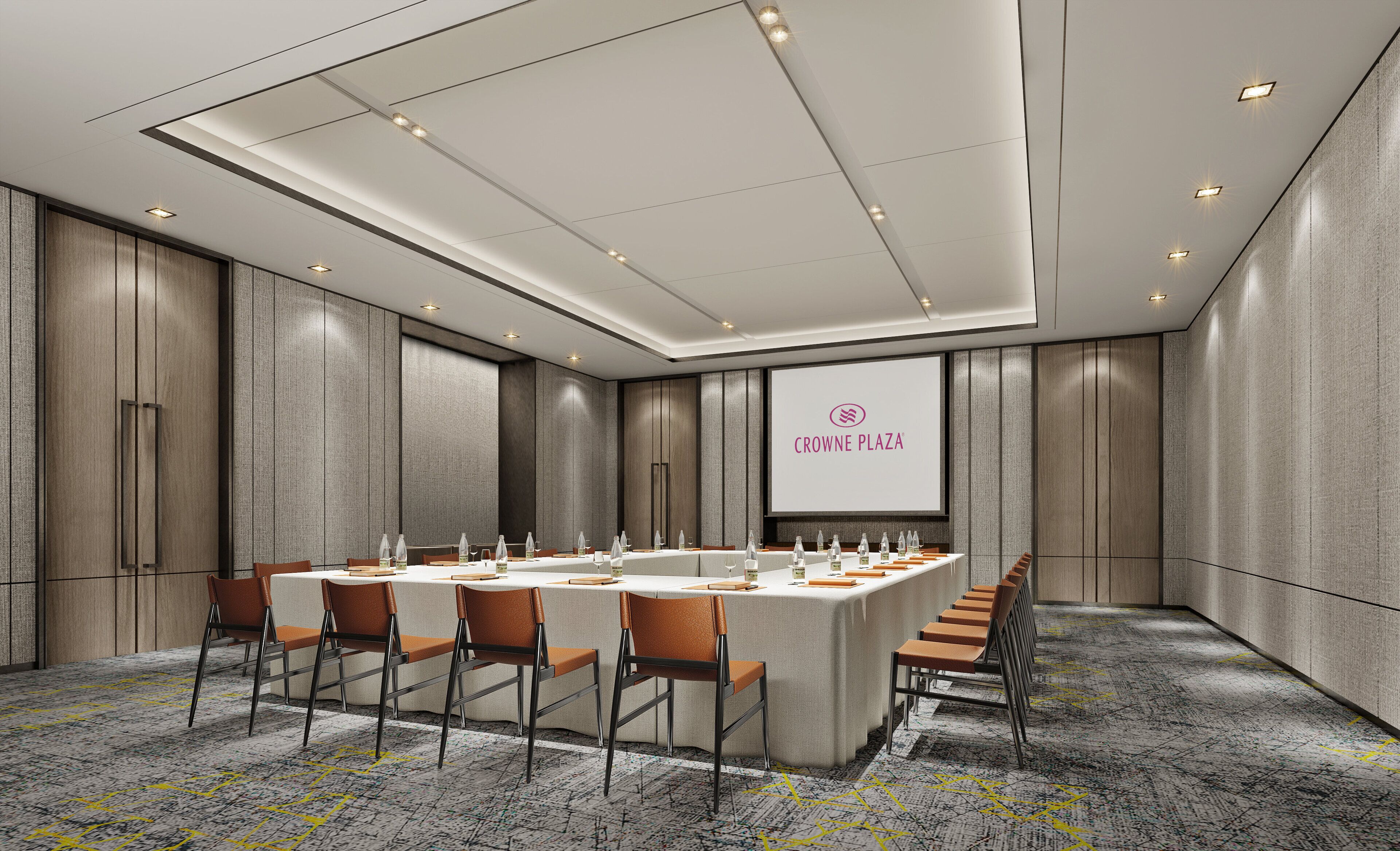 Un salón de conferencias con una larga mesa, sillas y una pantalla que muestra 'CROWNE PLAZA'.