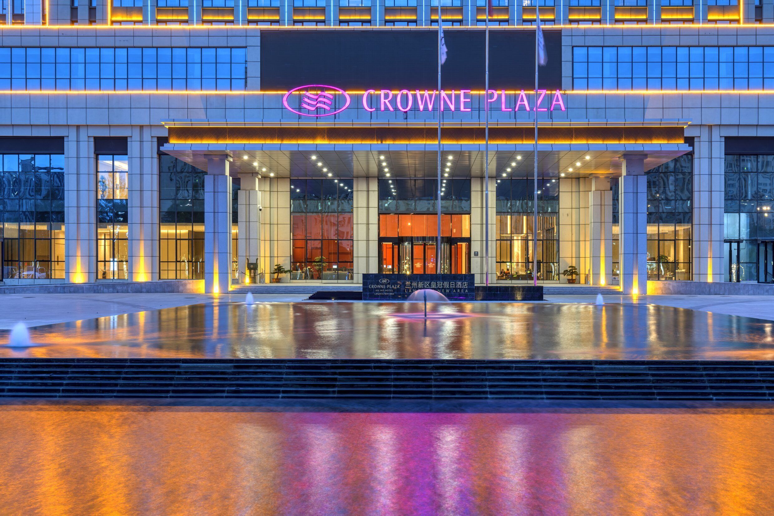 Esterno dell'hotel Crowne Plaza con un'ampia vasca d'acqua riflettente di fronte.