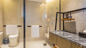Un baño moderno con ducha de vidrio, encimera de mármol y tocador de madera.