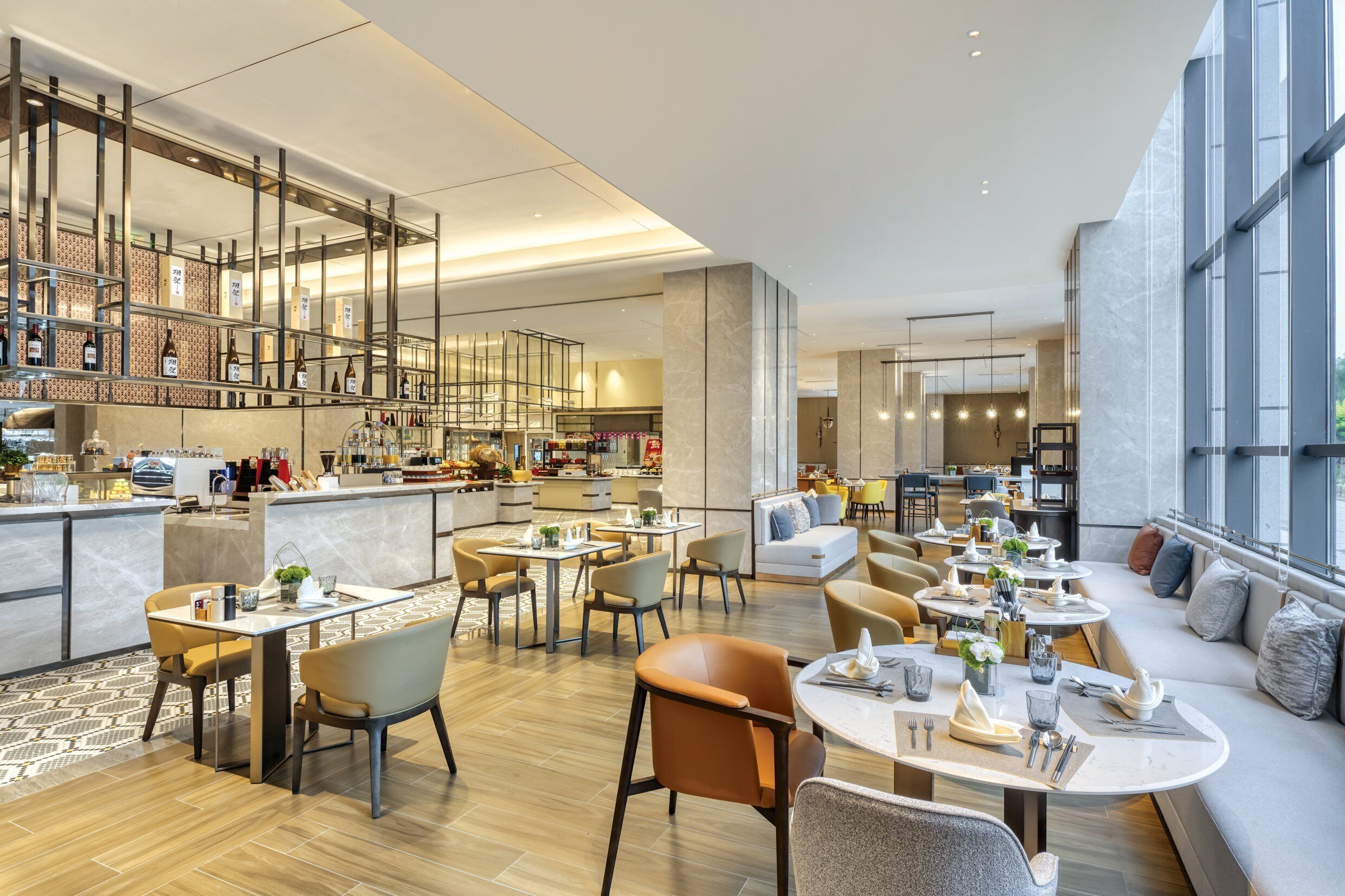Un hall d’hôtel moderne doté d’un bar, d’espaces aménagés pour s’asseoir et offrant une vue sur la ville.