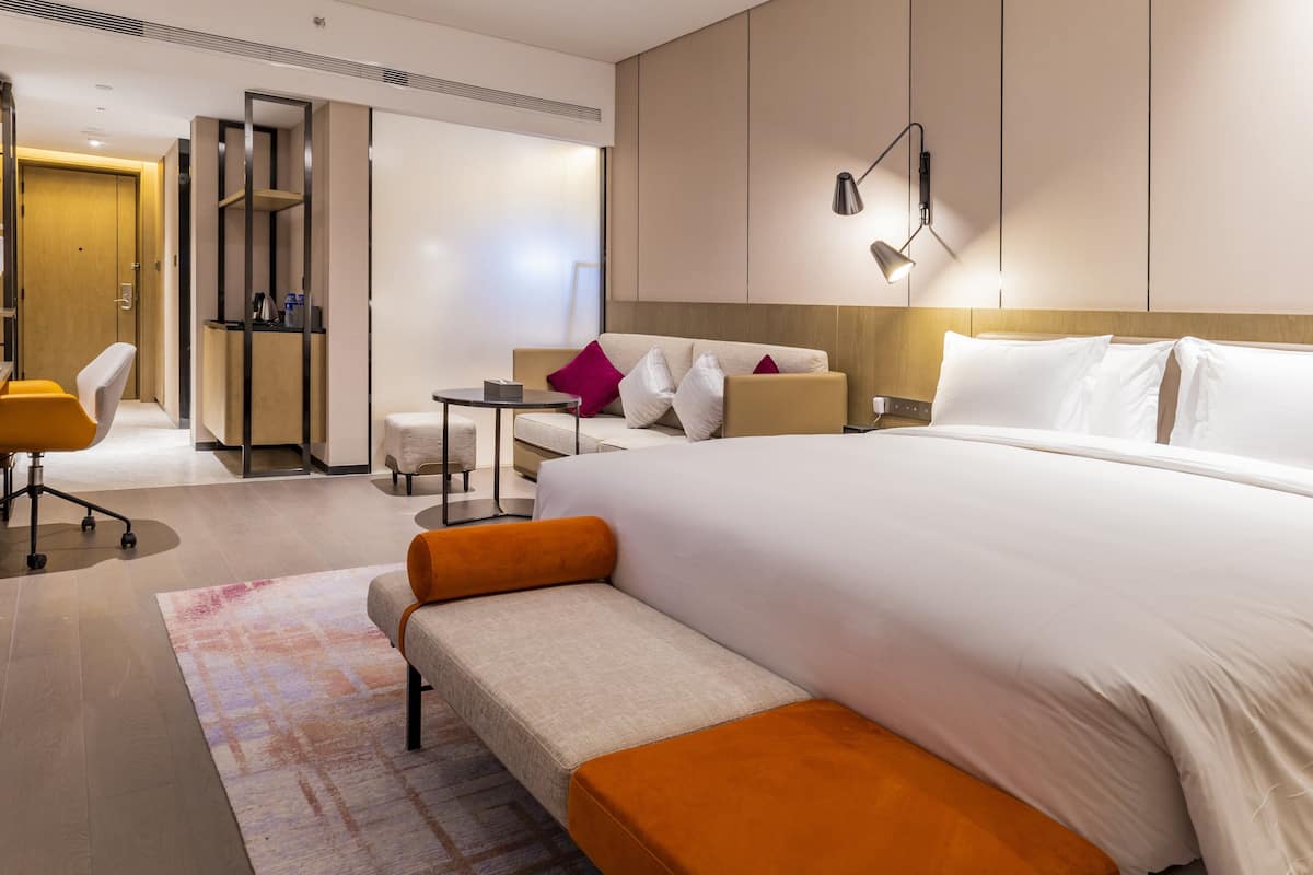 Une chambre d’hôtel moderne, dotée d’un grand lit, d’un canapé, d’un bureau et d’une chaise.