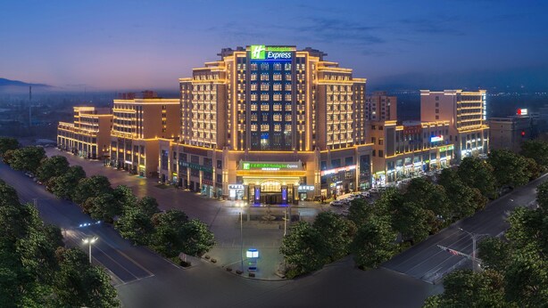 A multi-story hotel with a prominent 'Holiday Inn Express' sign, surrounded by trees and a parking area.