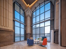 Un hall espacioso con amplias ventanas, chimenea y asientos modernos.
