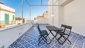 Ein Balkon mit Tisch und Stühlen, einem gemusterten Fliesenboden und Blick auf Gebäude.