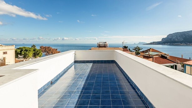 Eine Dachterrasse mit Blick auf das Meer und ferne Berge.