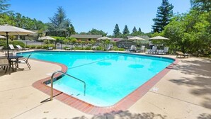 A rectangular swimming pool with a tiled edge, surrounded by lounge chairs and umbrellas.