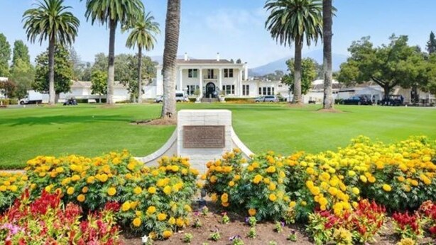 A large building with a lawn and palm trees in front.