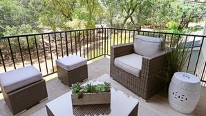 A balcony with wicker furniture, a planter box, and a white decorative item.