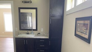 A modern kitchen with dark cabinetry, a marble countertop, and a built-in sink. - Terrific 4-bedroom house in Tylertown with WiFi, AC (Tylertown)