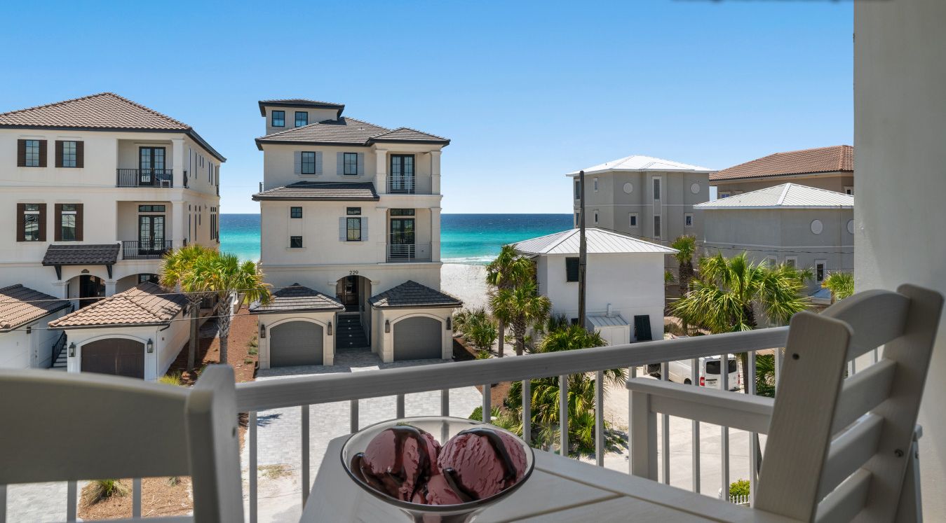 Et strandhotel med flere bygninger, en balkon med stol og is, og uhindret havudsigt.