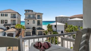 Et strandhotel med flere bygninger, en balkon med stol og is, og uhindret havudsigt.