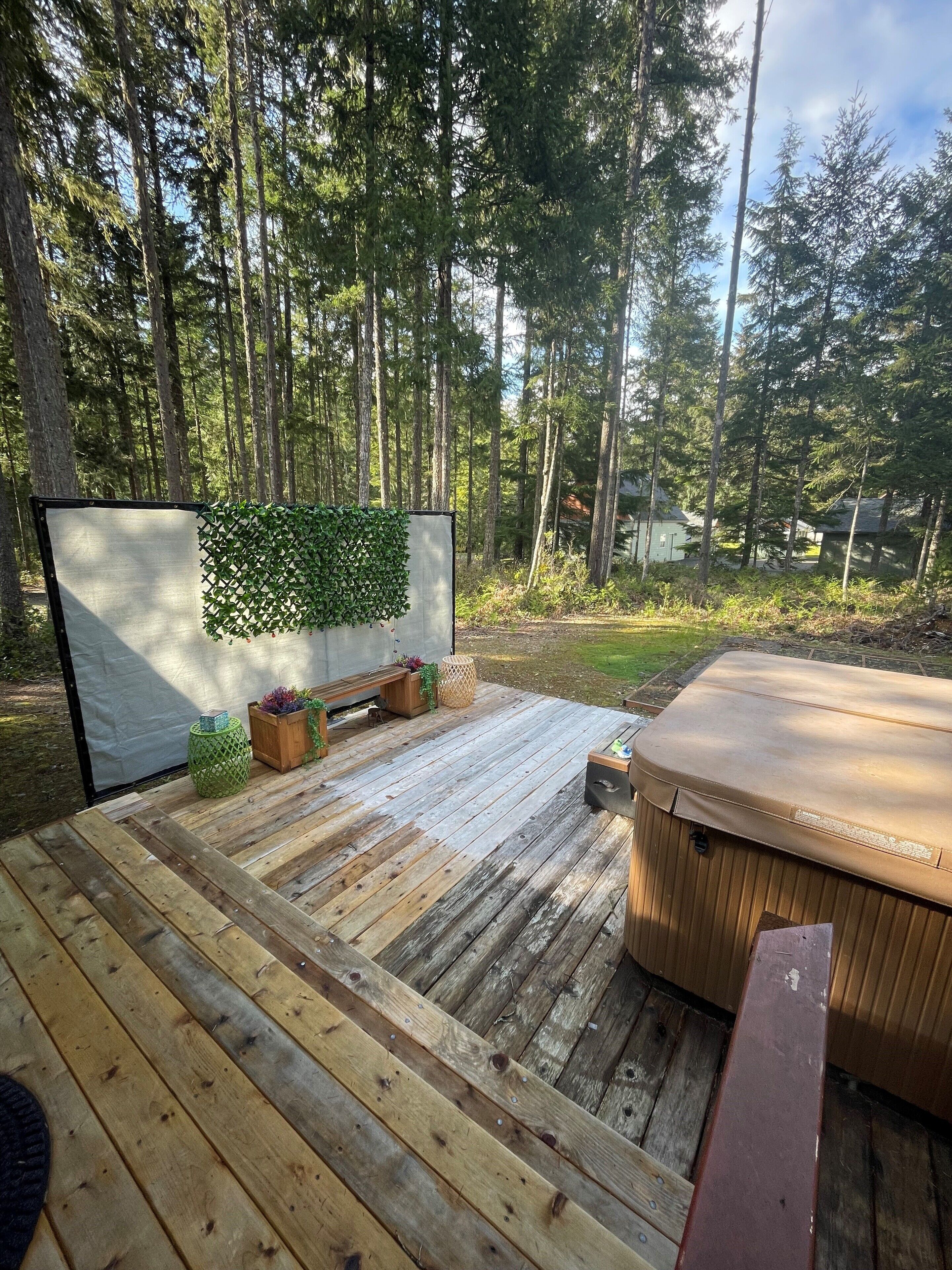 A wooden deck with a hot tub, a seating area, and a vertical garden.
