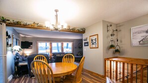 A dining area with a wooden table and chairs, a chandelier, and a staircase with a wooden railing. - Lakeside Bliss: Ideal Rental on Potato Lake close to Downtown Park Rapids  (Park Rapids)