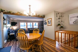 Ein Essbereich mit Holztisch und Stühlen, einer Kristallleuchter und einer Treppe mit Holzbalkon.