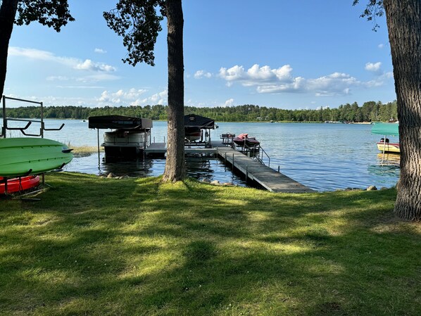 A dock extending into a calm lake with boats docked, surrounded by trees and grassy areas. - Lakeside Bliss: Ideal Rental on Potato Lake close to Downtown Park Rapids (Park Rapids)