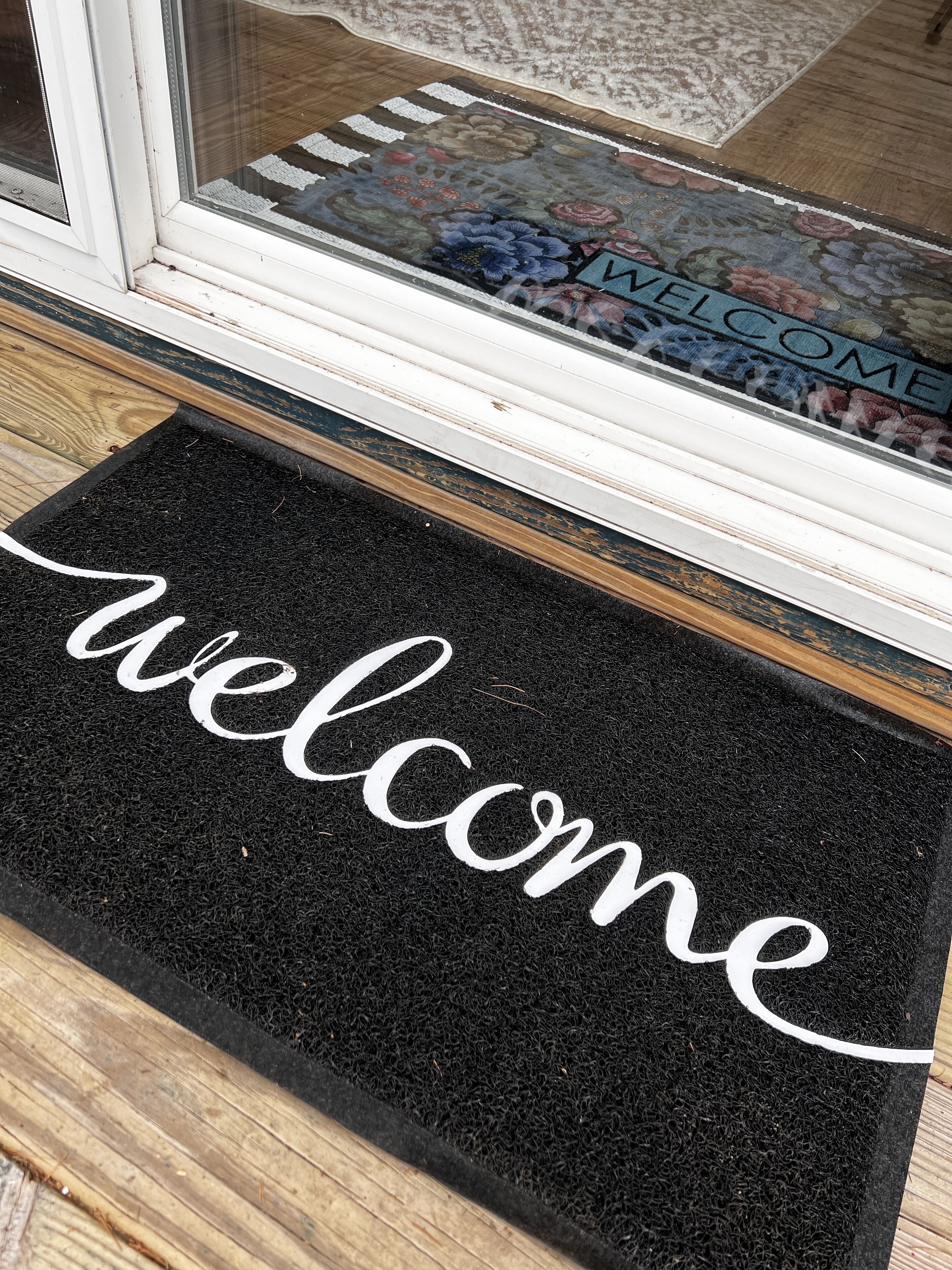 A black doormat with the word "welcome" in white cursive letters.