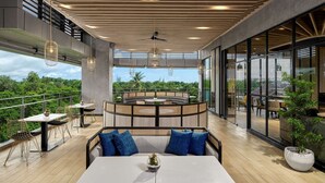 A modern outdoor dining area with a high ceiling, large windows, and a view of greenery. - Hyatt Place Makassar (Makassar)