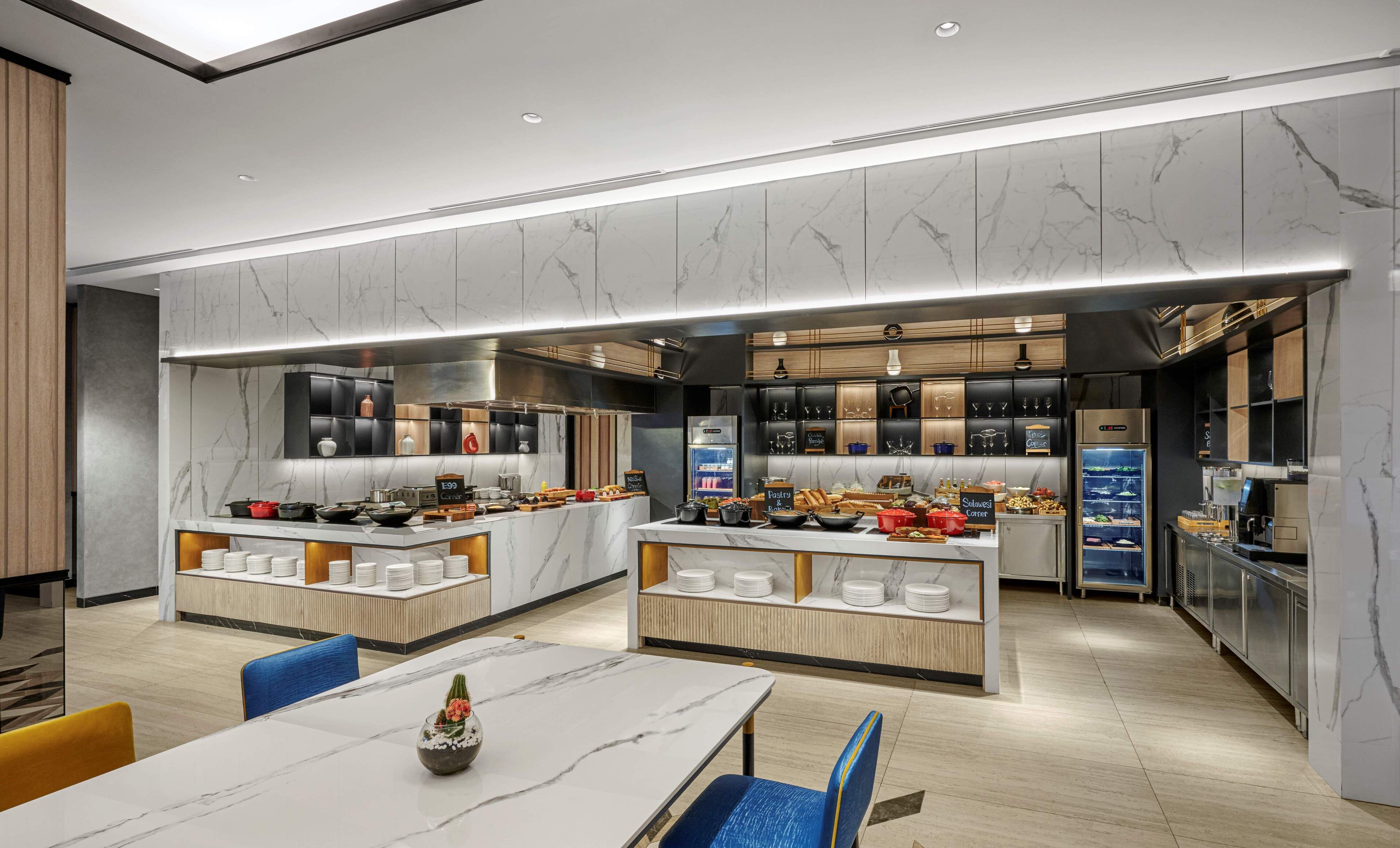 A modern kitchen with marble countertops, a central island with a coffee station, and a seating area with a table and chairs.