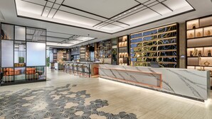 A modern bar area with a marble counter, bar stools, and a patterned floor. - Hyatt Place Makassar (Makassar)