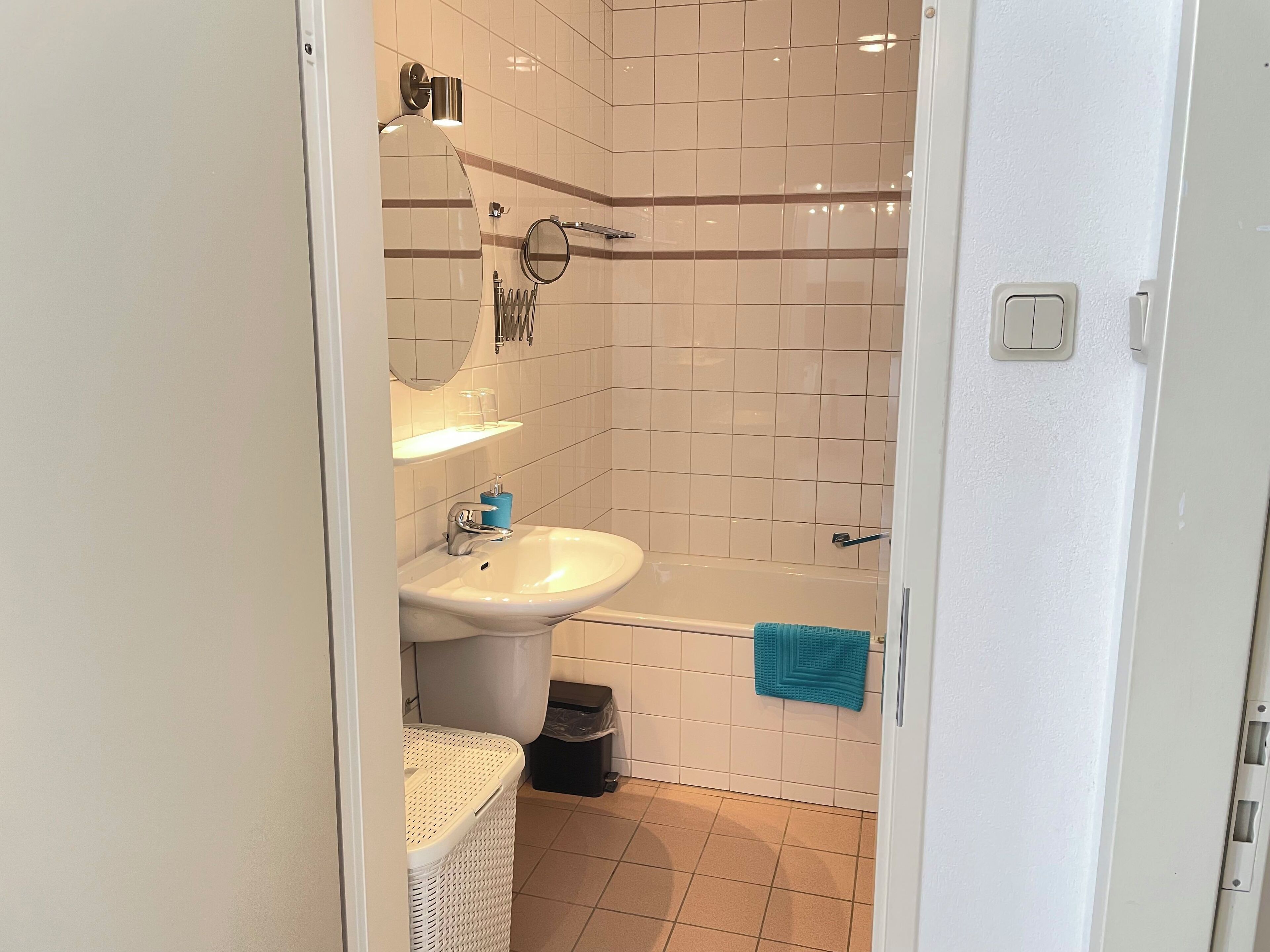 A bathroom with a white sink, a mirror, a towel rack, and a bathtub.