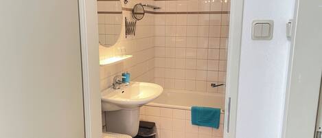 A bathroom with a white sink, a mirror, a towel rack, and a bathtub.