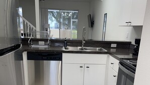 Eine moderne Küche mit Edelstahlgeräten, weißen Schränken und einer schwarzen Arbeitsplatte.