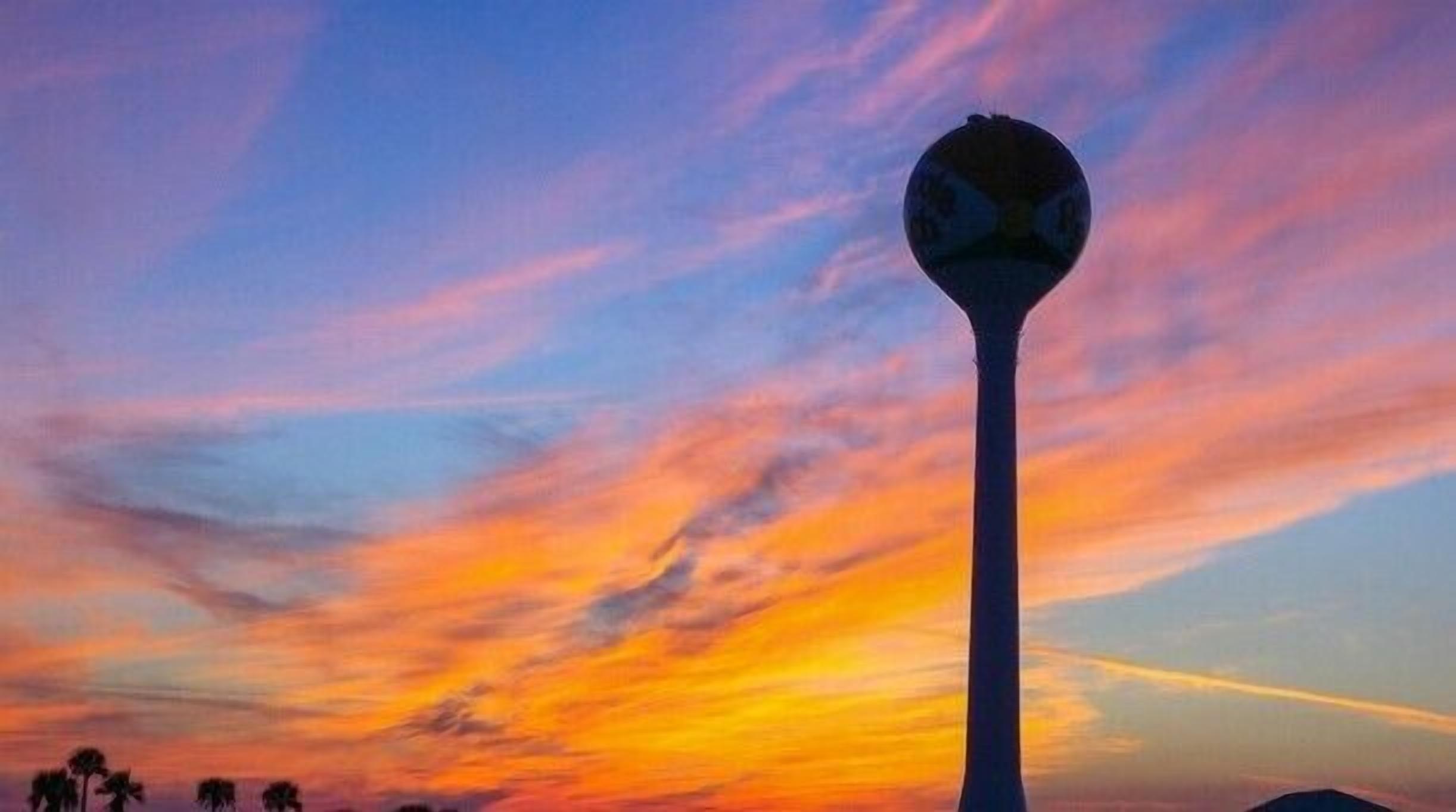 Ein hoher, zylindrischer Bau vor einem farbenprächtigen Sonnenuntergangshimmel.