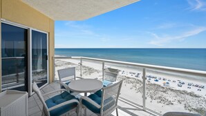 Un balcon doté de meubles en osier et offrant une vue sur la plage.