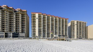 Un hôtel situé en bord de mer, composé de plusieurs immeubles de grande hauteur, doté de balcons et offrant un accès à une plage de sable.