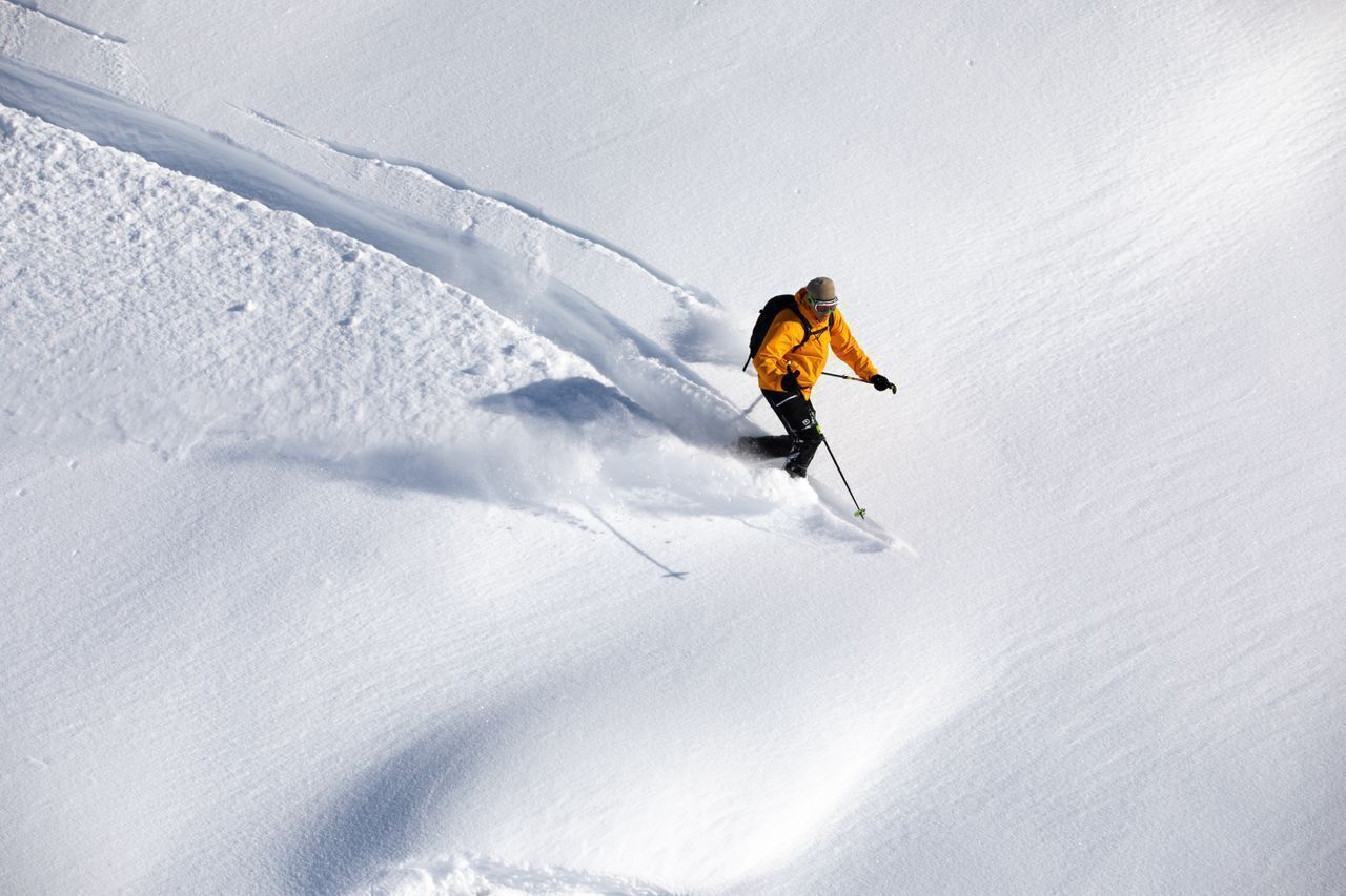 Une personne qui fait du ski sur une pente enneigée.
