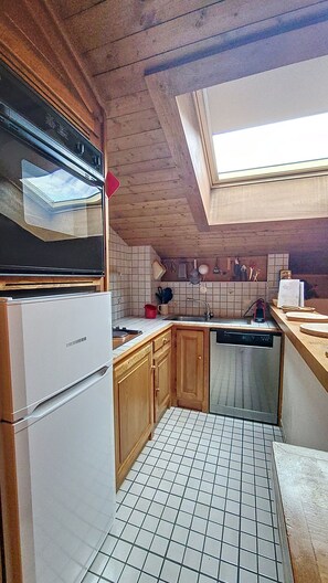 A compact kitchen with a built-in oven, a dishwasher, and a skylight.