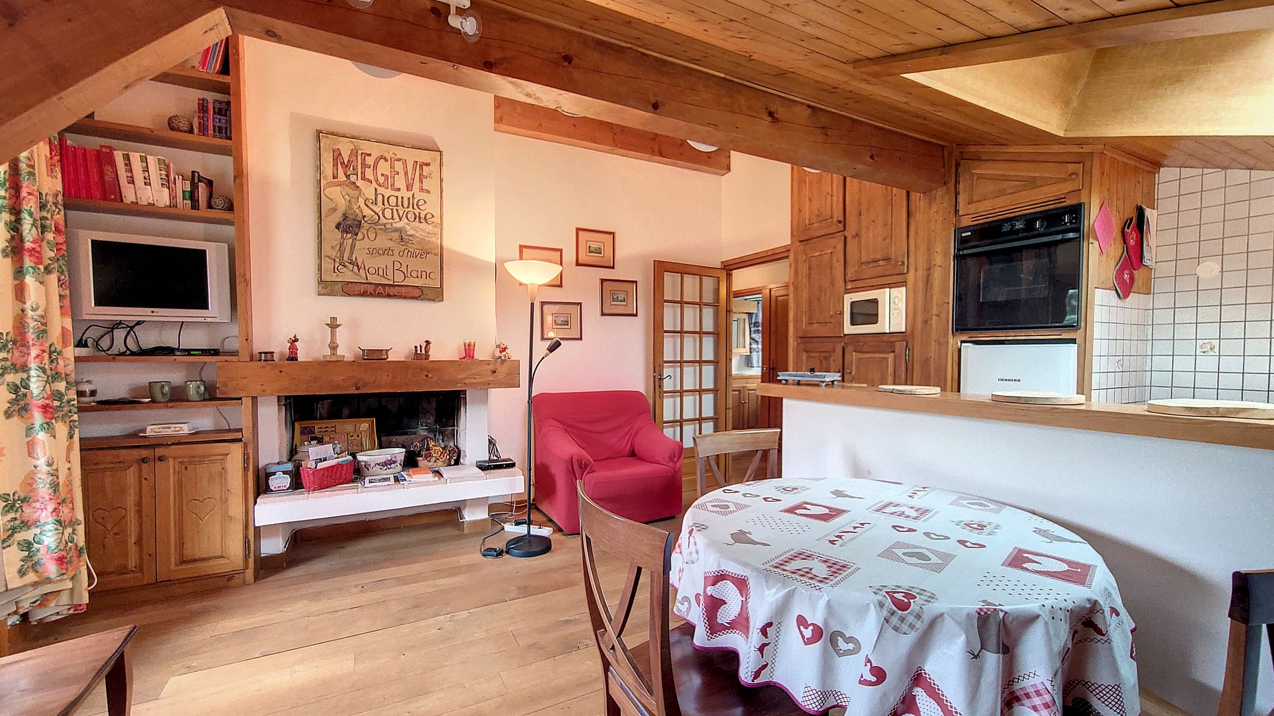 A cozy room with a fireplace, a red armchair, and a table with a tablecloth.