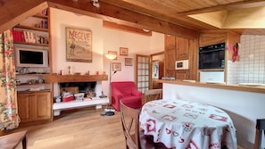 A cozy room with a fireplace, a red armchair, and a table with a tablecloth. - 1 Sporting Charmille - (Megève)