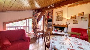 A cozy room with a fireplace, a television, and a dining table. - 1 Sporting Charmille - (Megève)