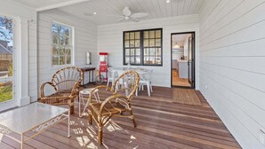 Une terrasse couverte avec une table et des chaises, un ventilateur de plafond et une vue sur le jardin arrière.