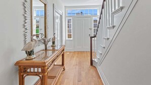 Un couloir avec une console en bois, un grand miroir et une porte blanche au fond.