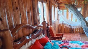 Una habitació rústica de fusta amb un llit, una cadira espanyola i un capçal de llit de fusta.