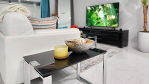 Un salon moderne avec un canapé, une table basse, un téléviseur et une plante en pot.