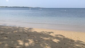 A beach with a calm sea, a boat in the distance, and a clear sky. - Beach Villa in Dorado del Mar! Walk to the beach, restaurants, pool, casino (Dorado)