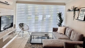 A modern living room with a flat-screen TV, a sofa, a coffee table, and a chair. - Beach Villa in Dorado del Mar! Walk to the beach, restaurants, pool, casino (Dorado)
