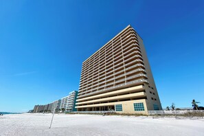 Un hotel alto con varios balcones, cerca de una playa.