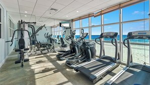 A gym with treadmills, elliptical machines, and weight equipment. Large windows offer a view of the beach. - GULF-FRONT CONDO, INDOOR/OUTDOOR POOL, BEACH ACCESS! (Gulf Shores)